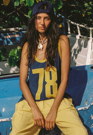 A woman wearing a navy blue athletic tank top with yellow trim and the number 78