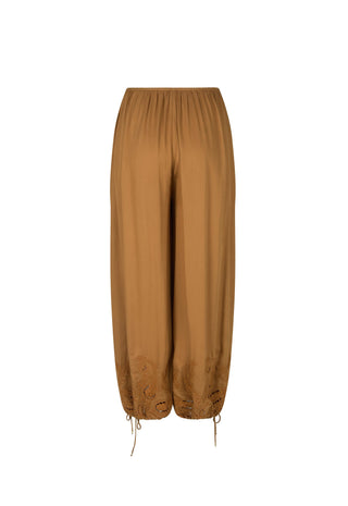 A pair of loose, wide-leg harem-style pants in a warm camel brown color, featuring a gathered elastic waistband and drawstring ankle cuffs with embroidered detailing near the lower hems, shown against a plain white background.