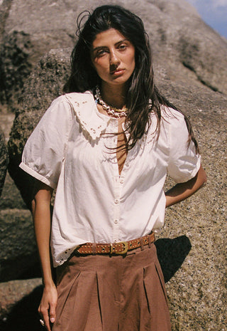 A woman wearing a white linen shirt with lace trim