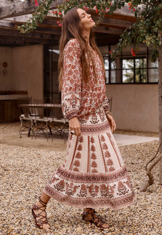  standing on a gravel patio in front of a rustic wooden structure.